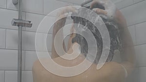 Woman in the shower, back side of young female showering under refreshing water, healthy lifestyle. Girl washing long