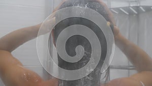 Woman in the shower, back side of young female showering under refreshing water, healthy lifestyle. Girl washing long