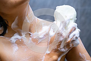 Woman shower with body scrub sponge