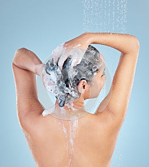 Woman, shower and hair for shampoo in studio with back for cleaning, growth and dandruff by blue background. Girl