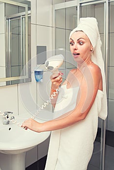 The woman after the shower was about to dry her hair,but the hair dryer was broken.