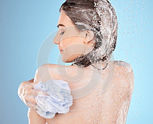 Woman, shower and wash for skincare hygiene, health or wellness against a blue studio background. Female washing in body