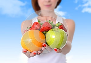 Woman showing apple, orange fruit and strawberries in hands in diet healthy nutrition concept