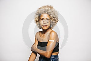 Woman showing the band-aid on her arm after vaccination