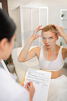 Woman showing a beauty doctor how to change her face.