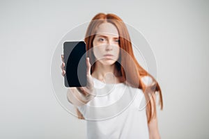 Woman showing blank smartphone screen. Focus on smartphone.