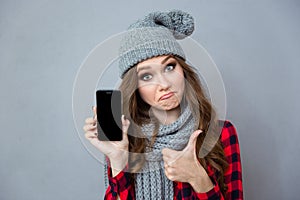 Woman showing blank smartphone screen and thumb up