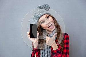 Woman showing blank smartphone screen and thumb up