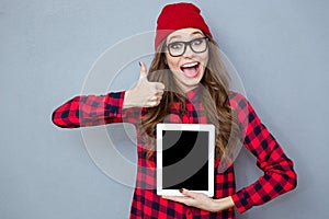 Woman showing blank tablet computer screen and thumb up