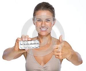 Woman showing blistering package of pills and thumbs up photo