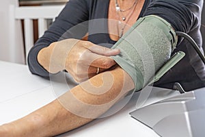 Woman is showing the correct use of a blood pressure monitor