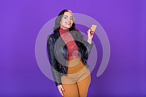 Woman showing a credit card on purple background. Shopping concept