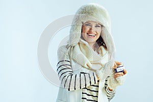 Woman showing creme against winter light blue background