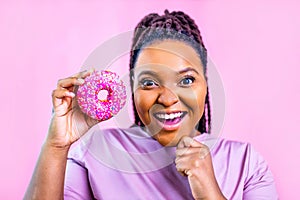 woman showing donut eyas glasses in pink studio background