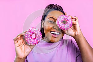 woman showing donut eyas glasses in pink studio background