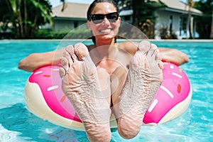 Woman showing feet got wrinkly stayed in a pool