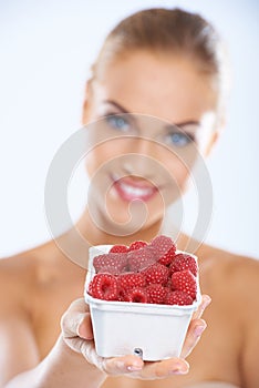 Woman showing fresh and nutritious raspberries