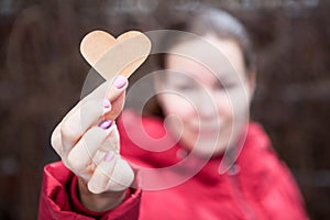 Woman showing heart shape in stretched hand, red jacket, blurred head