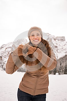 Woman showing heart shaped hands among snow-capped mountains