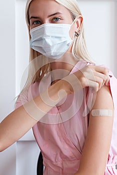 Woman showing her arm with bandage after receiving vaccination.