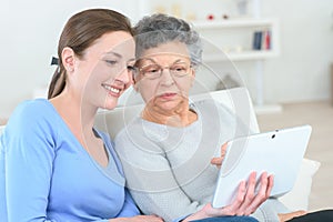 Woman showing grandmother how to use digital tablet