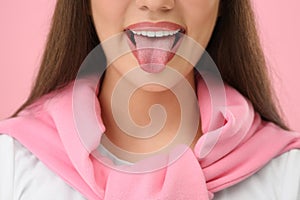 Woman showing her tongue on pink background, closeup