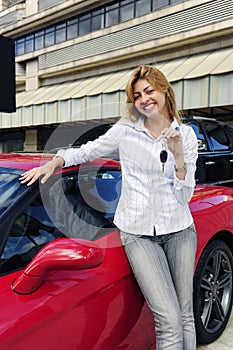 Woman showing key of new red sports car