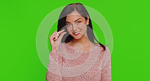 Woman showing a little bit gesture with sceptic smile, showing minimum sign, measuring small size