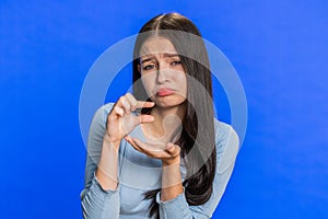 Woman showing a little bit gesture with sceptic smile showing minimum sign measuring small size