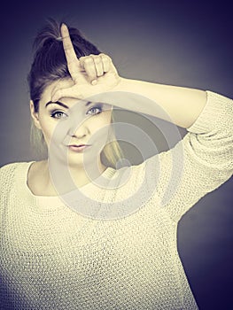 Woman showing loser gesture with L on forehead