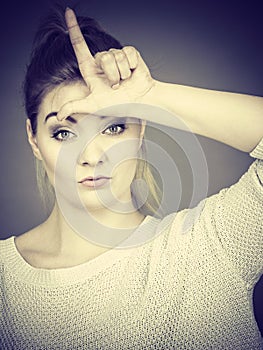 Woman showing loser gesture with L on forehead