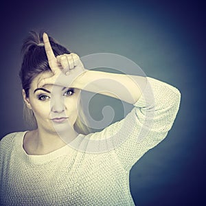 Woman showing loser gesture with L on forehead