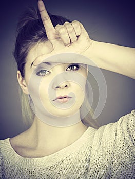 Woman showing loser gesture with L on forehead