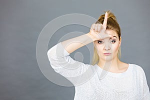 Woman showing loser gesture with L on forehead