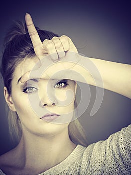 Woman showing loser gesture with L on forehead