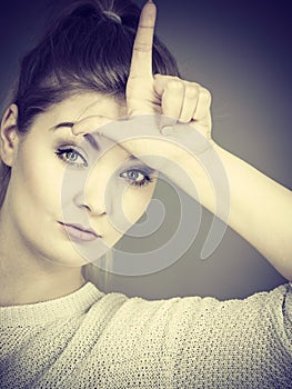 Woman showing loser gesture with L on forehead