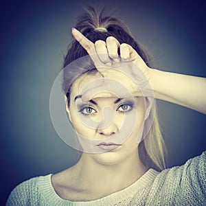 Woman showing loser gesture with L on forehead