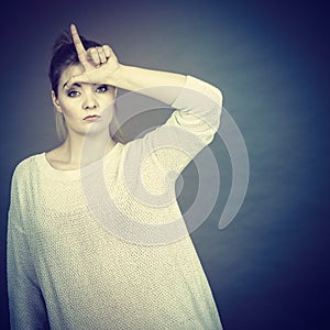 Woman showing loser gesture with L on forehead