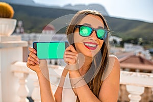 Woman showing phone with empty screen on beautiful white city background