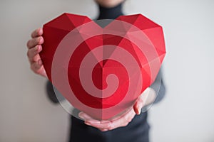 Woman showing red polygonal paper heart shape