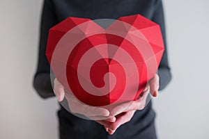 Woman showing red polygonal paper heart shape