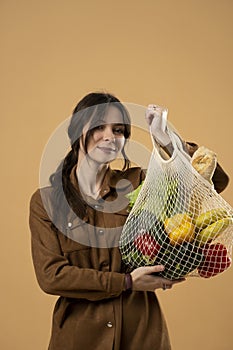 Woman showing a reusable mesh shopping bag full of fresh groceries. Zero waste. Ecologically and environmentally