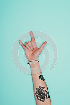 Woman showing rock sign isolated on turquoise