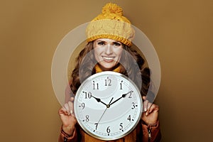 Woman showing round clock remind about autumn time change
