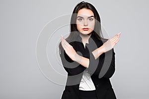Woman showing a stop arms crossed on a gray background.