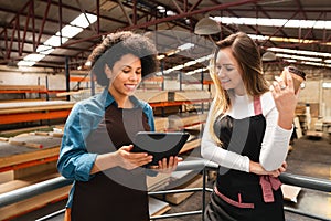 Woman showing tablet to female colleague at storehouse