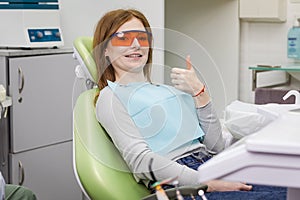 Woman showing thumb up sign at dentist`s office clinic