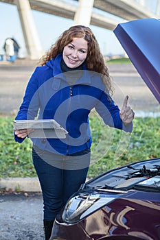 Woman showing thumb up standing in front of car