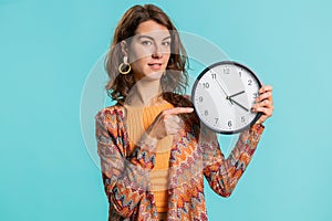 Woman showing time on wall office clock, ok, thumb up, approve, pointing finger at camera, your time