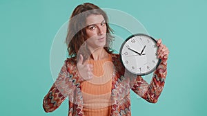 Woman showing time on wall office clock, ok, thumb up, approve, pointing finger at camera, your time